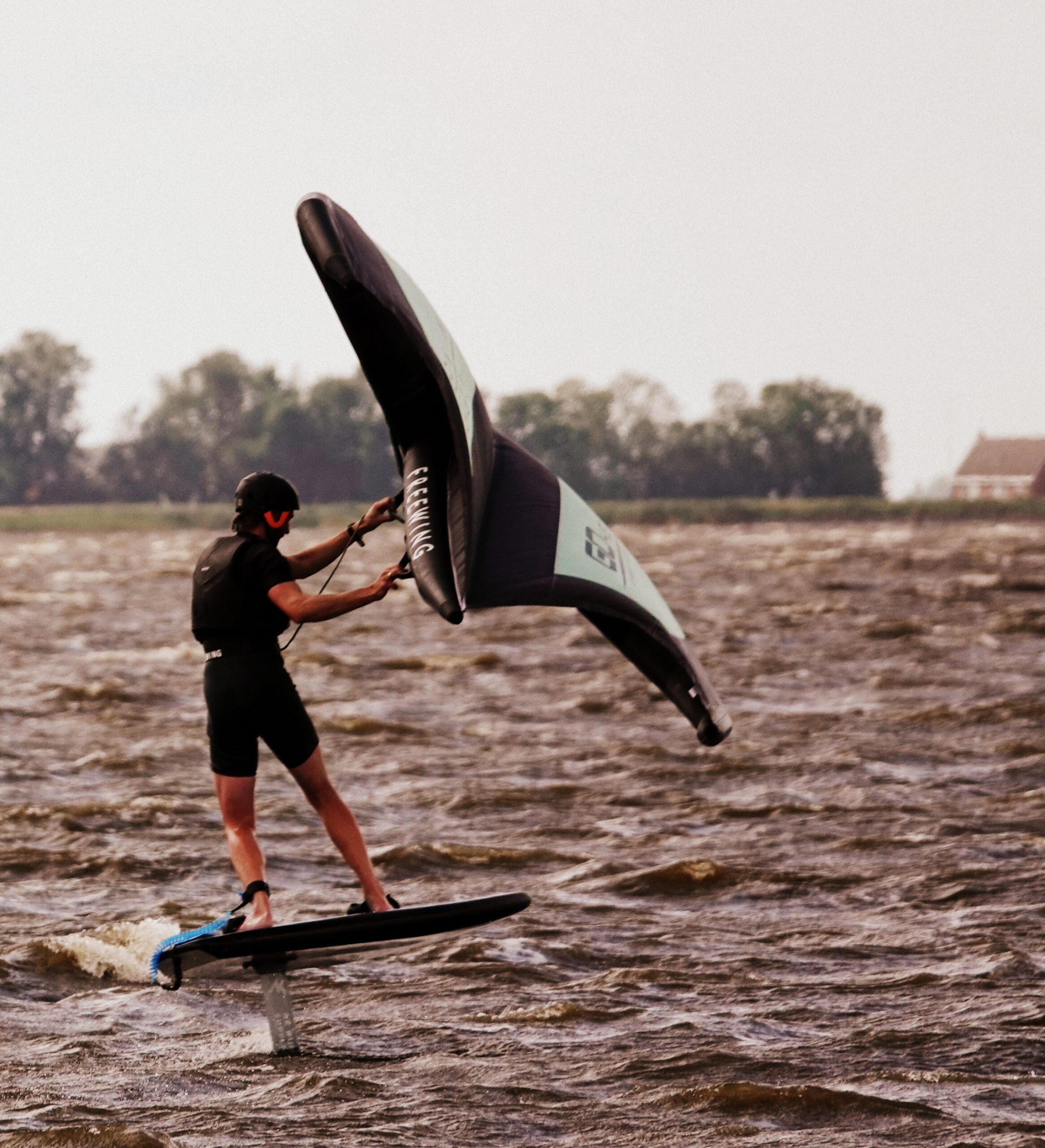 Wingfoilen zweven over het water met een wing in handen van de surfer.